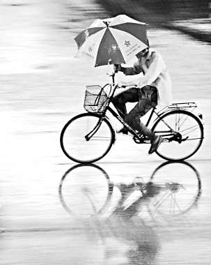 北京部分地区7月30至31日连续降雨,一名市民在海淀区冒雨骑车前行